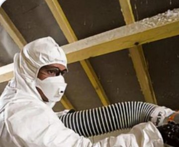 Technicien soufflant de l'isolant dans des combles
