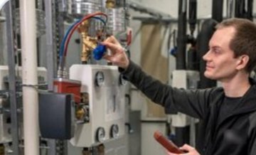 Technicien réglant un réseau d'eau chaude sanitaire en chaufferie